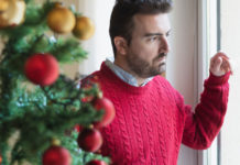 Holidays when you’re not feeling good man looking on the window at christmas time