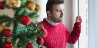 Holidays when you’re not feeling good man looking on the window at christmas time